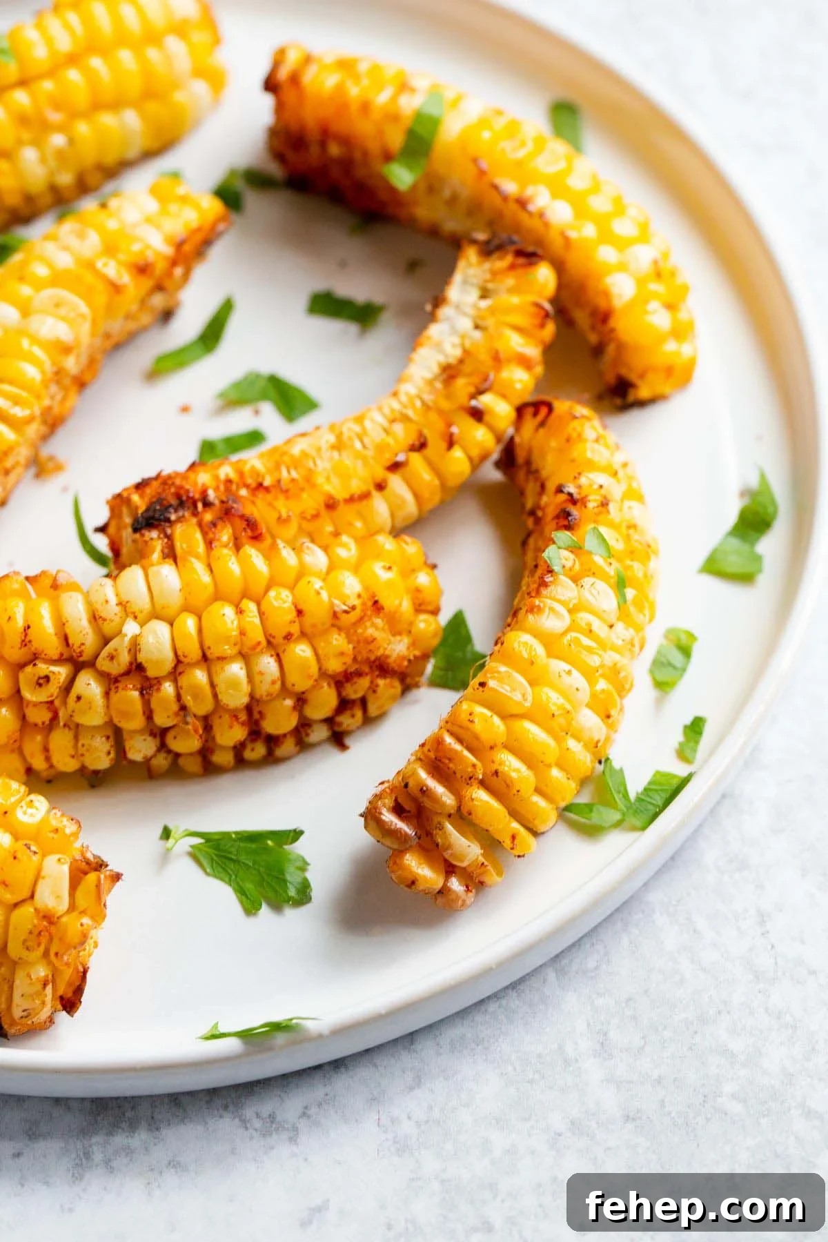 Crispy Air Fryer Corn Ribs Recipe for Summer BBQs 8 Corn ribs on a white plate with parsley.