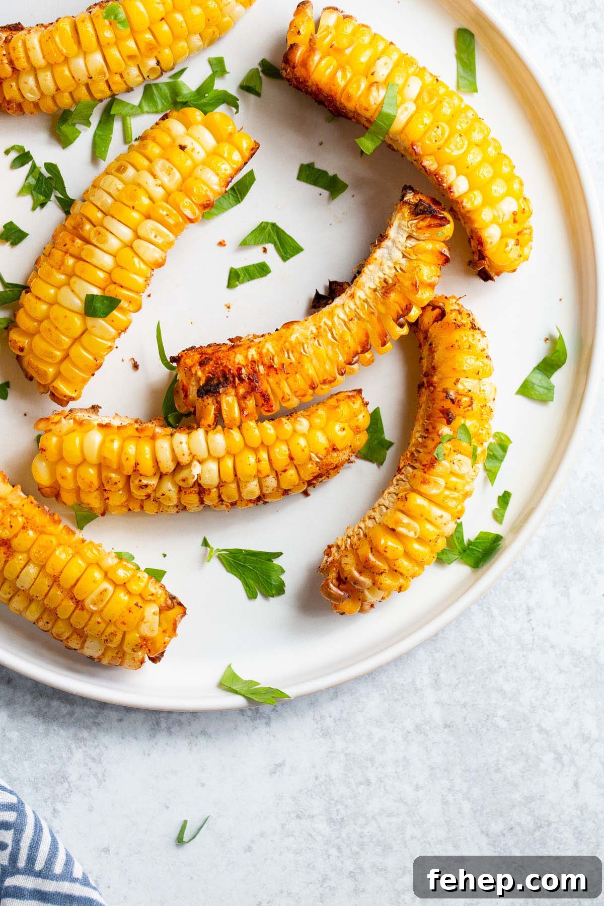 Crispy Air Fryer Corn Ribs Recipe for Summer BBQs 9 Corn ribs on a white plate with parsley.