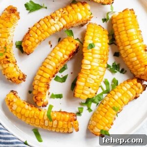 Crispy Air Fryer Corn Ribs Recipe for Summer BBQs 10 Corn ribs on a white plate with parsley.
