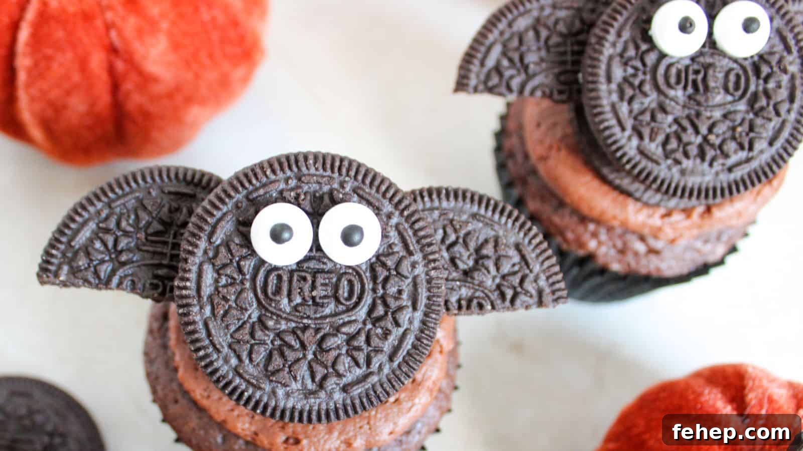 11 Spooky Halloween Treats to Liven Up Any October Night 13 Chocolate cupcakes decorated with Oreo cookies resembling bats, complete with candy eyes. Orange pumpkins are visible in the background.