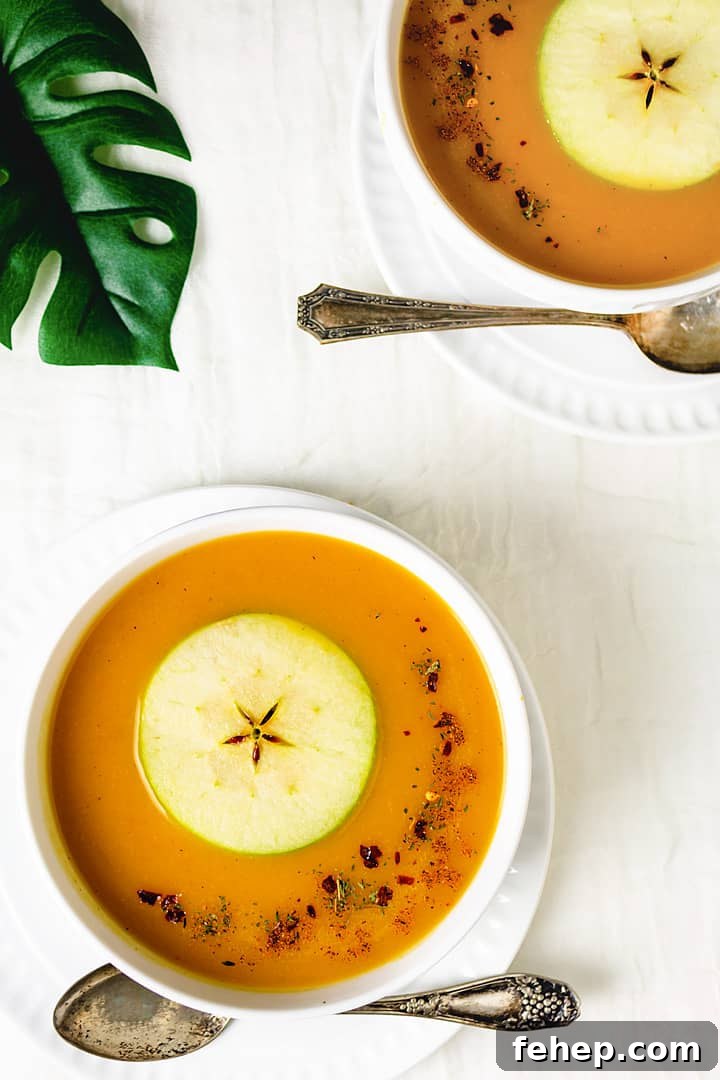 Butternut Squash and Apple Soup Recipe for Cozy Fall Nights 6 Two bowls of soup with spoons on a white tablecloth and green leaf