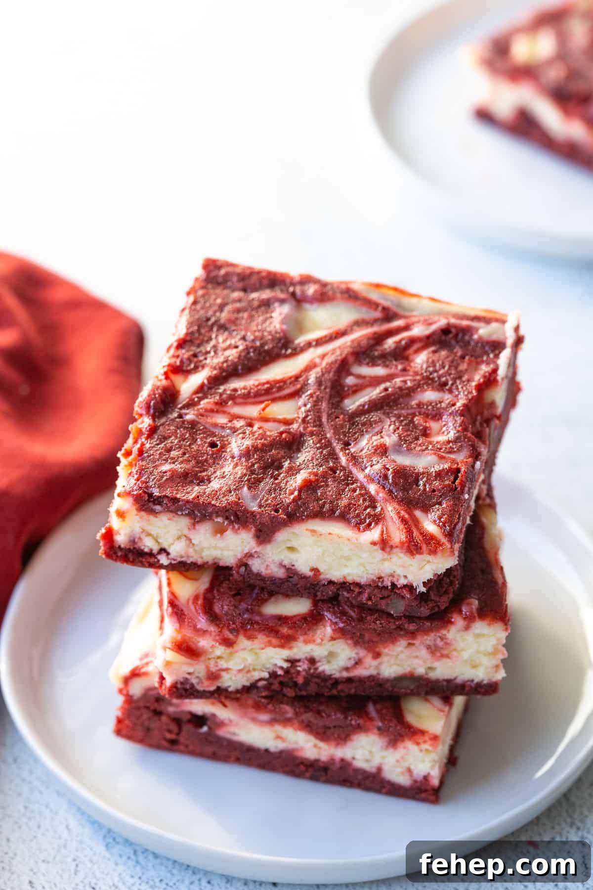 three red velvet brownies stacked on a white plate.