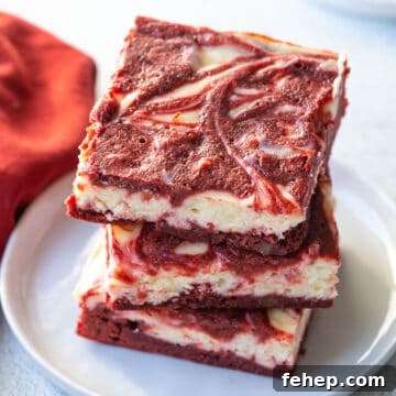 three red velvet brownies stacked on a white plate.