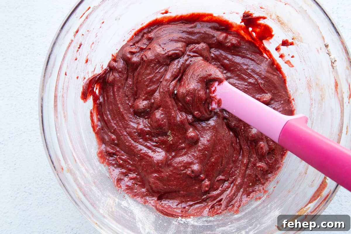 red velvet brownie batter in a glass bowl with a pink spatula.