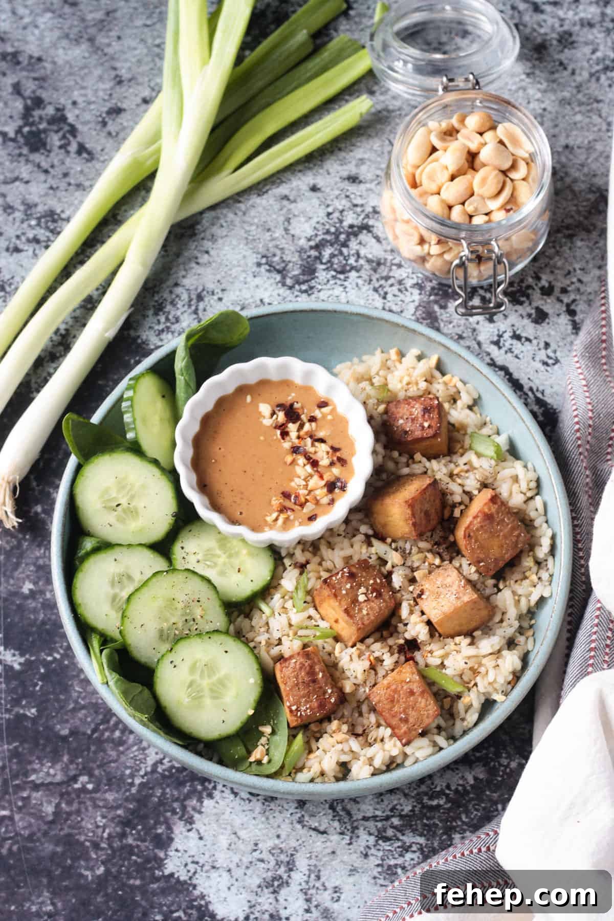 Flavorful Marinated Baked Tofu Recipe for Crispy, Savory Tofu 2 Baked tofu over rice with a side of cucumbers and peanut sauce.