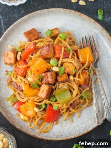 Kung Pao Tofu with noodles on a plate with two forks.