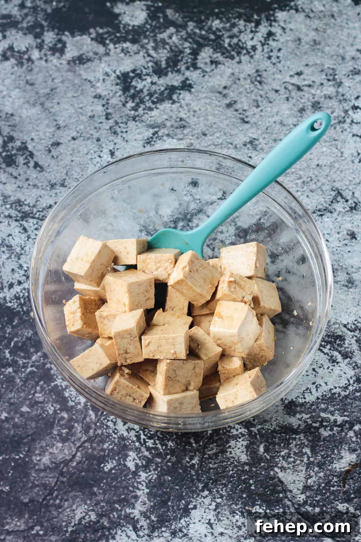 Flavorful Marinated Baked Tofu Recipe for Crispy, Savory Tofu 5 tofu cubes marinating in a glass bowl