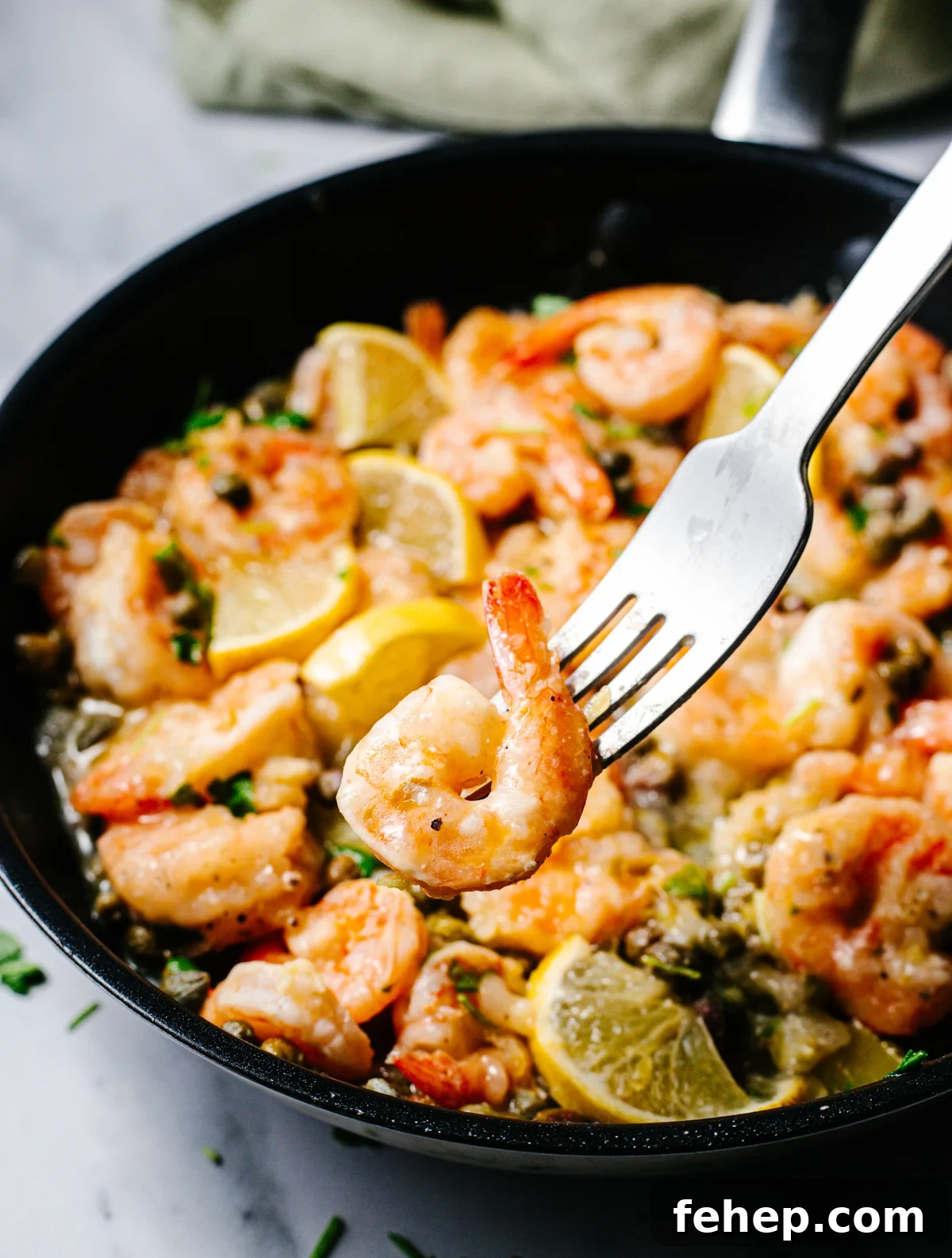 Shrimp Piccata in a skillet with one shrimp on a fork.