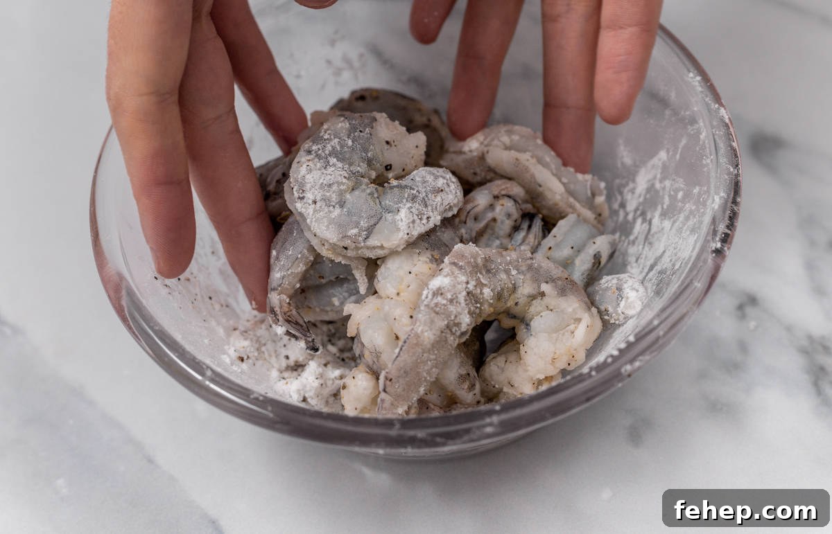 tossing raw shrimp with cornstarch in glass bowl