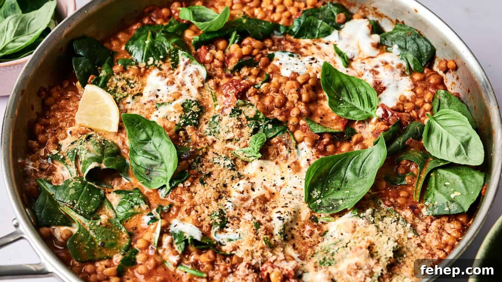 11 Marry Me Recipes That Impress Without Fuss 10 A pan of lentil dish with spinach, fresh basil, tomato sauce, and melted cheese, garnished with lemon wedges.