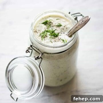 vegan tzatziki sauce in a glass jar with a spoon inside and fresh dill