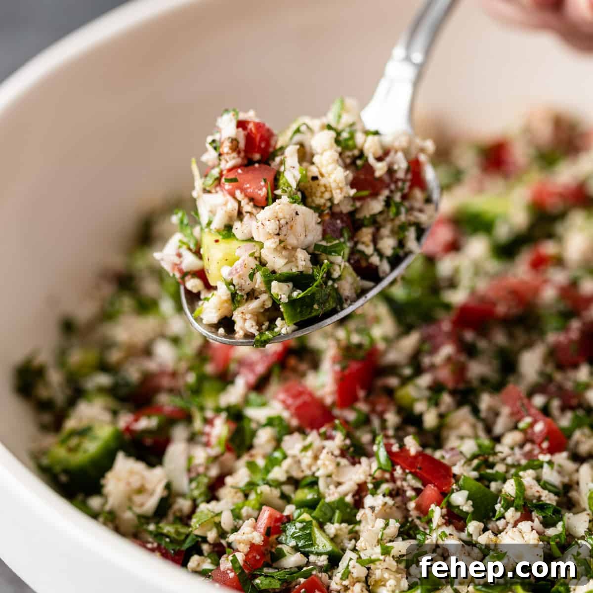 Cauliflower Tabbouleh Salad with Fresh Herbs and Lemon Vinaigrette 2 close up: cauliflower tabbouleh in a spoon over a bowl