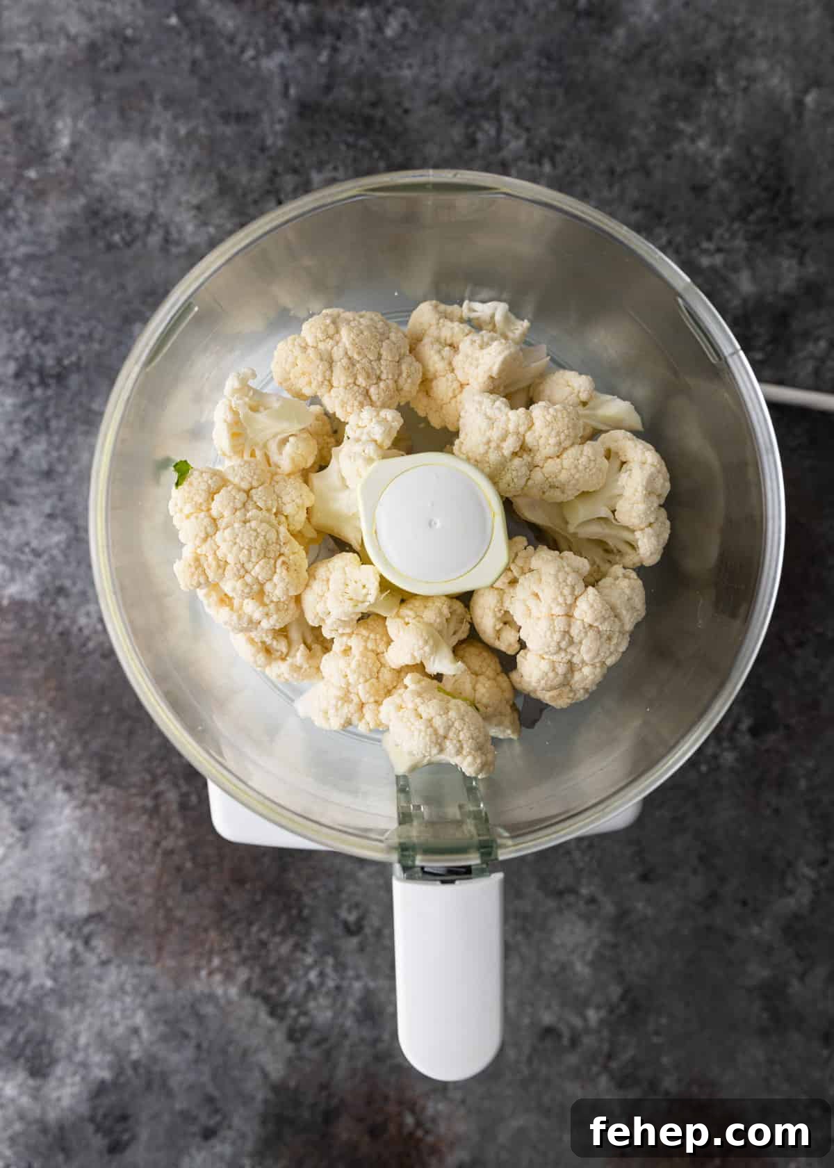 Cauliflower Tabbouleh Salad with Fresh Herbs and Lemon Vinaigrette 5 overhead: raw cauliflower in a food processor