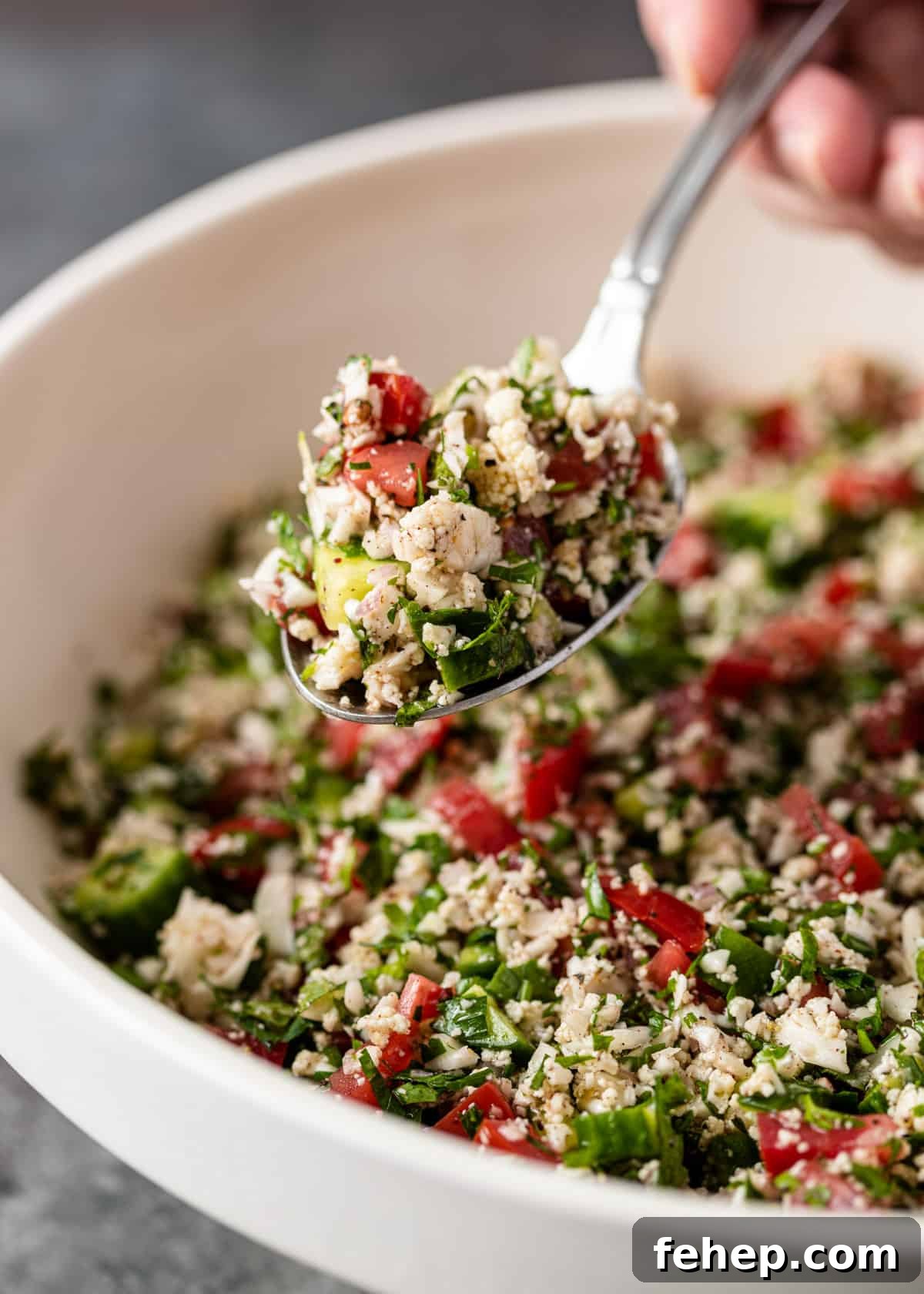 Cauliflower Tabbouleh Salad with Fresh Herbs and Lemon Vinaigrette 9 close up of cauliflower tabbouleh in a spoon over a bowl