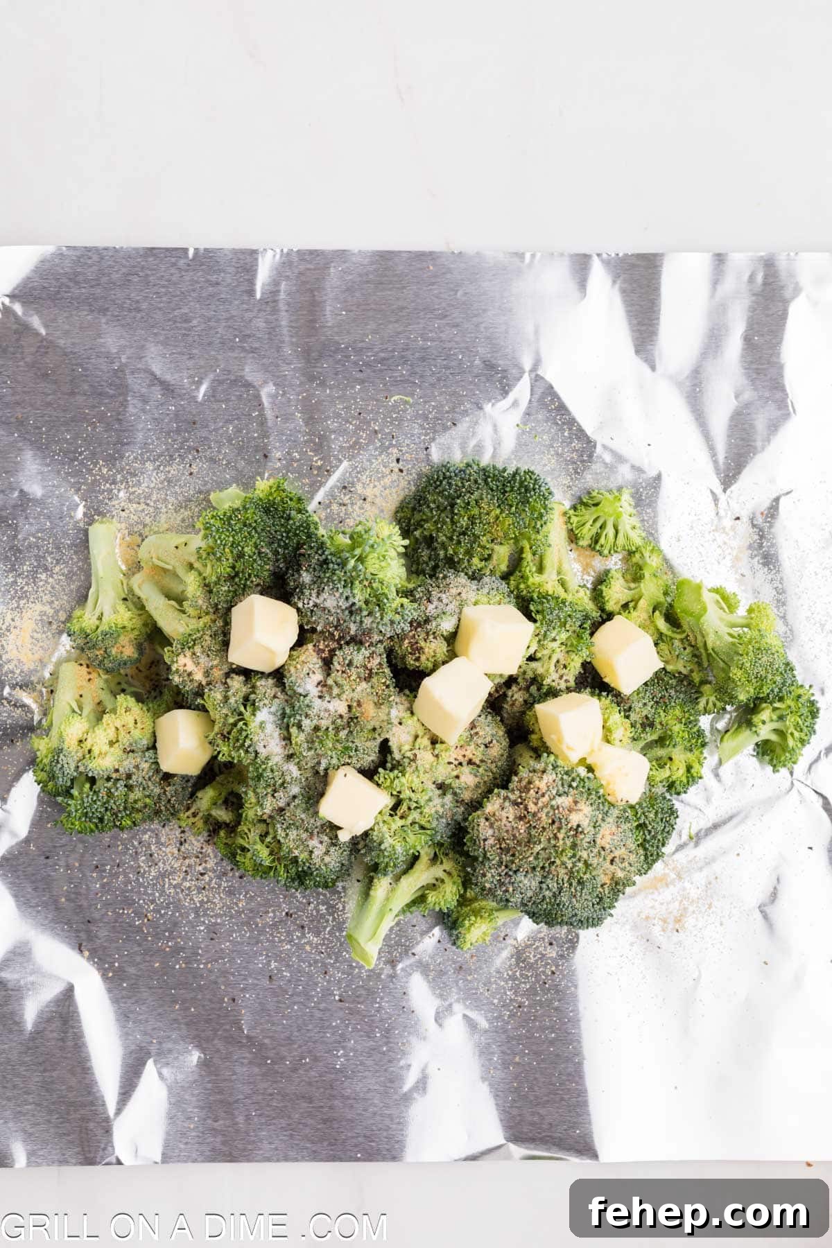 Broccoli on foil topped with butter and seasoning