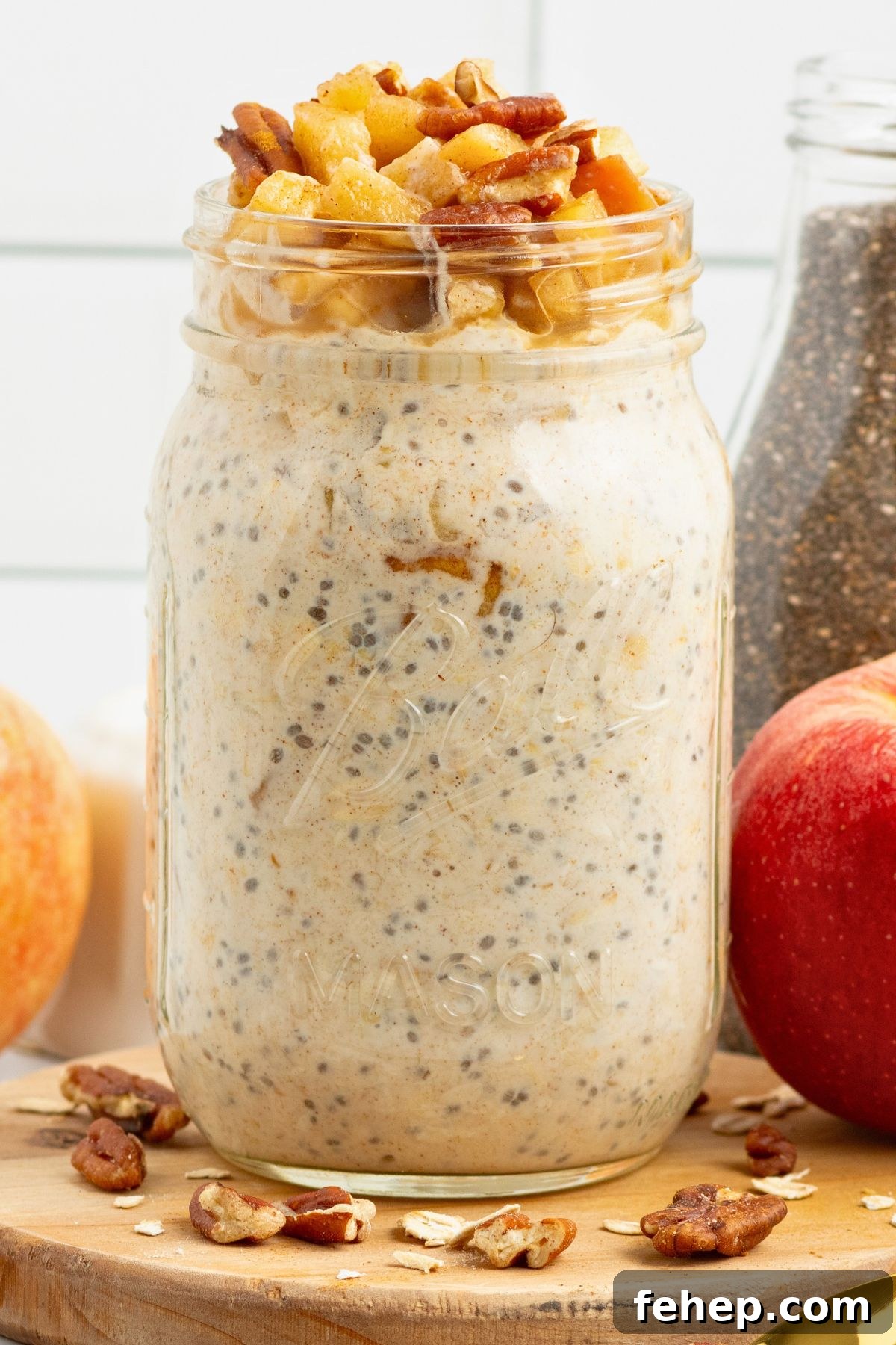 Creamy yogurt mixed with oats and apple slices in a mason jar making apple pie overnight oats. 