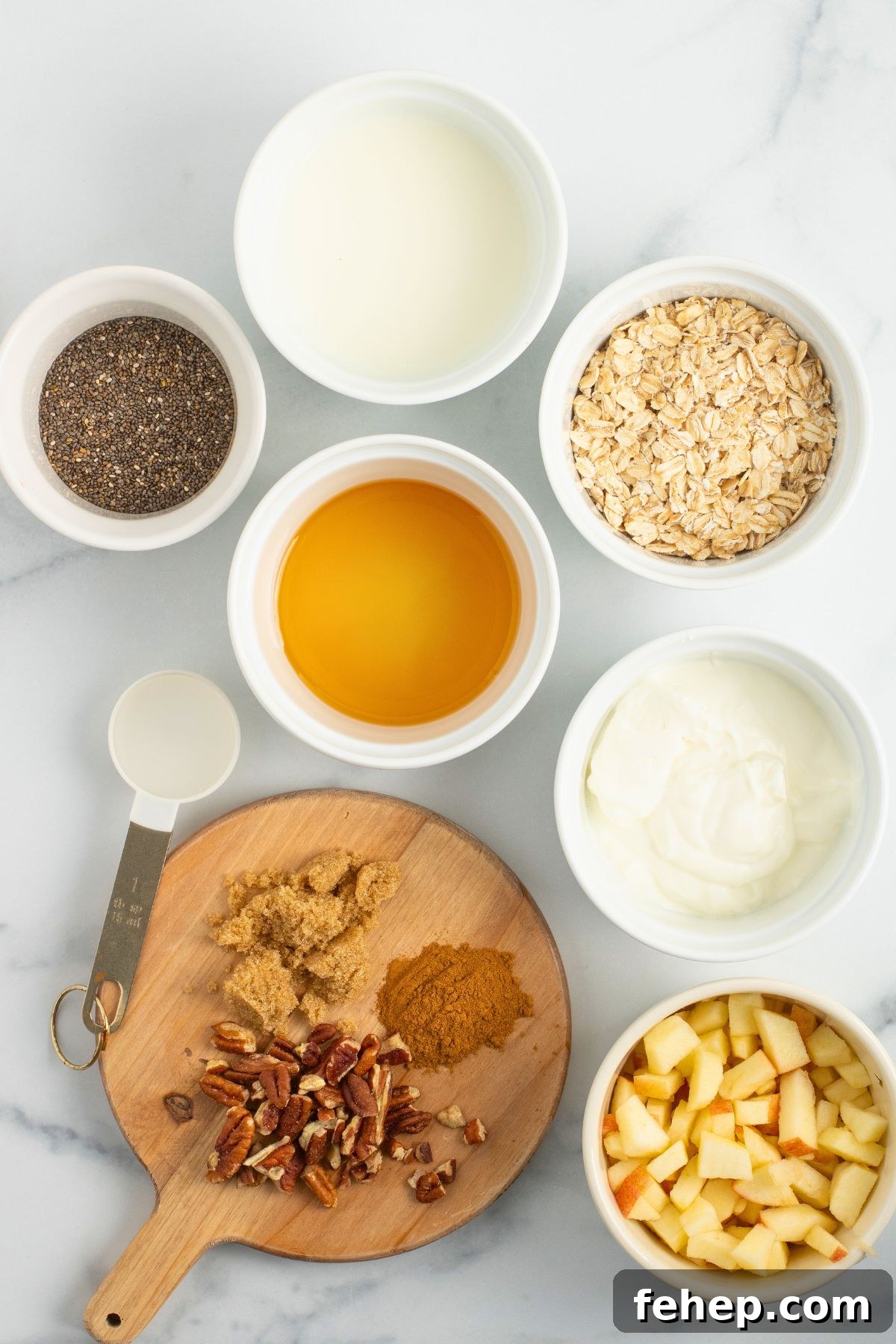 Ingredients needed to make overnight oats measured out in small bowls on a marble table. 