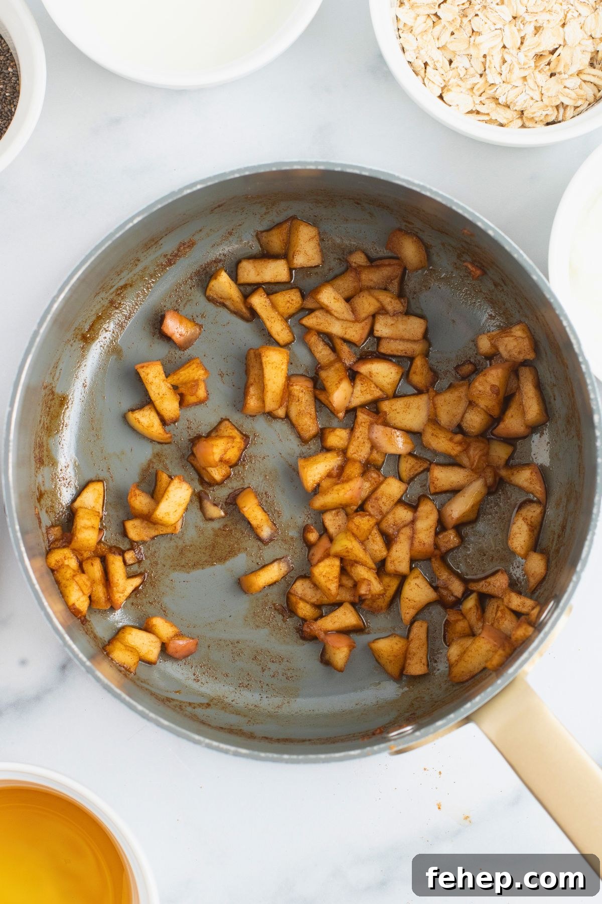 Cooked apples in a saucepan, coated with spices. 