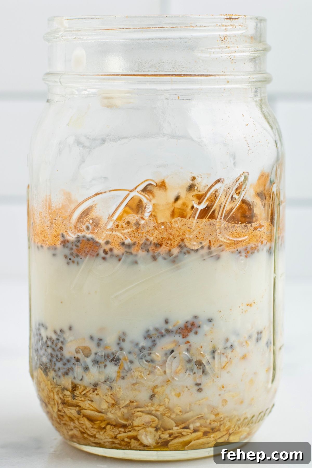 Layers of oats, yogurt, and fruit, in a clear mason glass. 