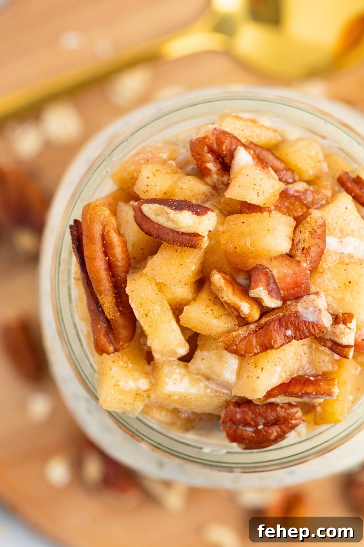 Overhead photo of apple pie overnight oats in a mason jar, topped with chopped apples and nuts. 