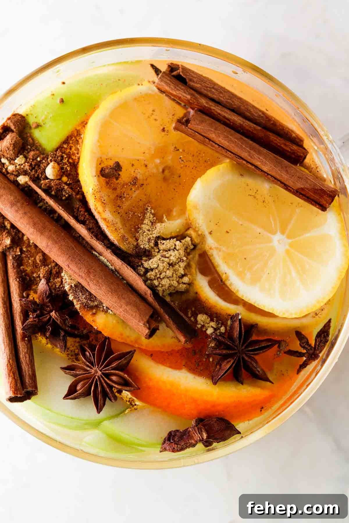 Cozy Fall Simmer Pot Recipe for a Home-Filling Autumn Scent 5 Spices, lemons, oranges, and apples in a large glass pot.