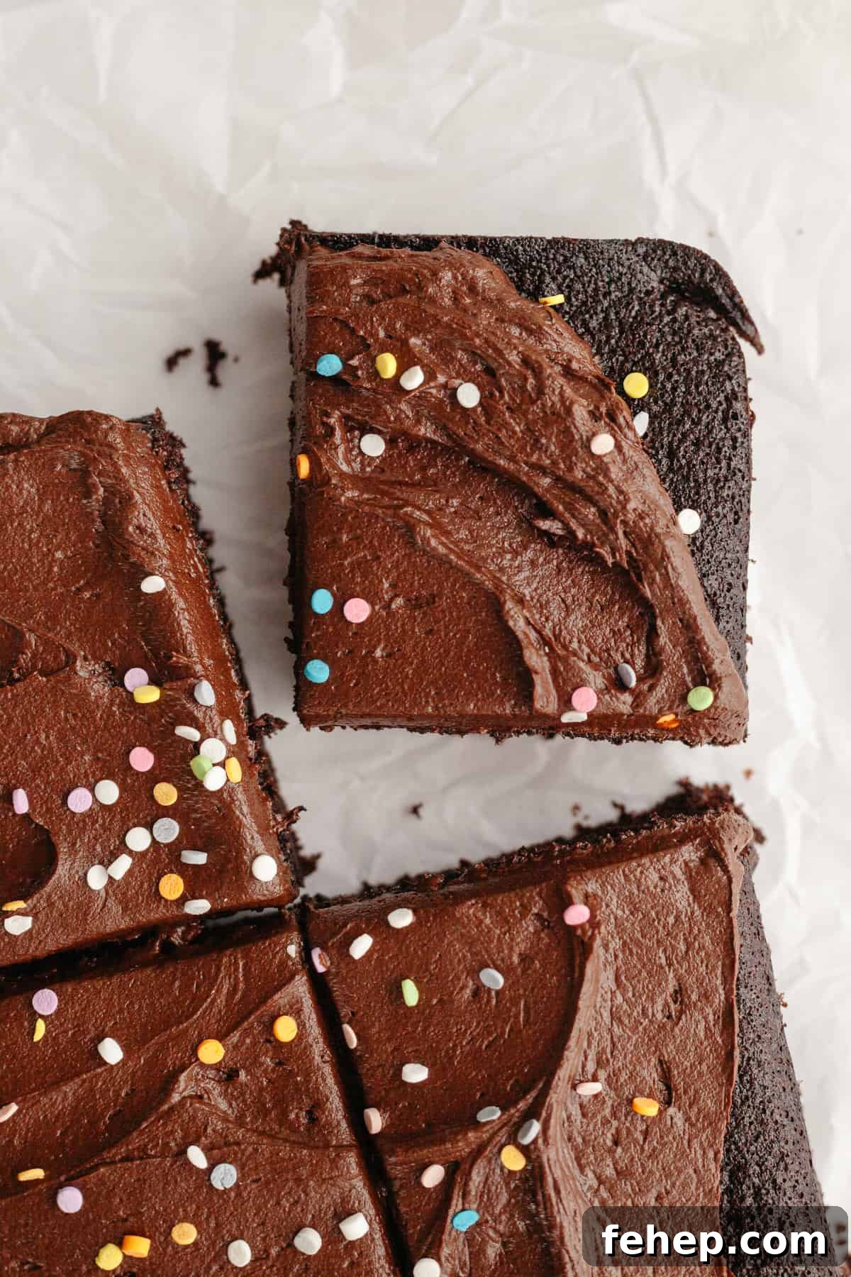 Slices of chocolate sheet cake with chocolate frosting and rainbow sprinkles.