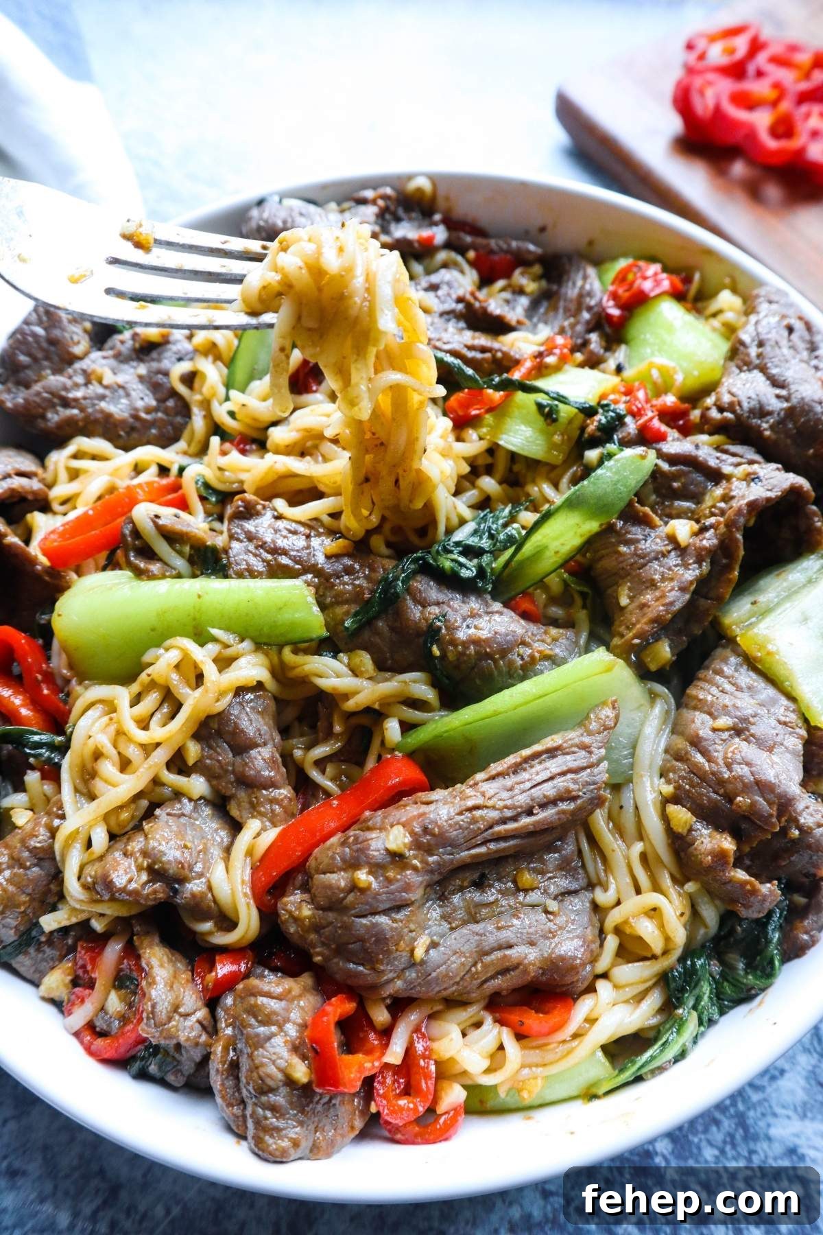 Stir-Fried Vietnamese Pho with Beef and Noodles 7 white plate with fork pulling noodles surrounded by vegetables and beef.