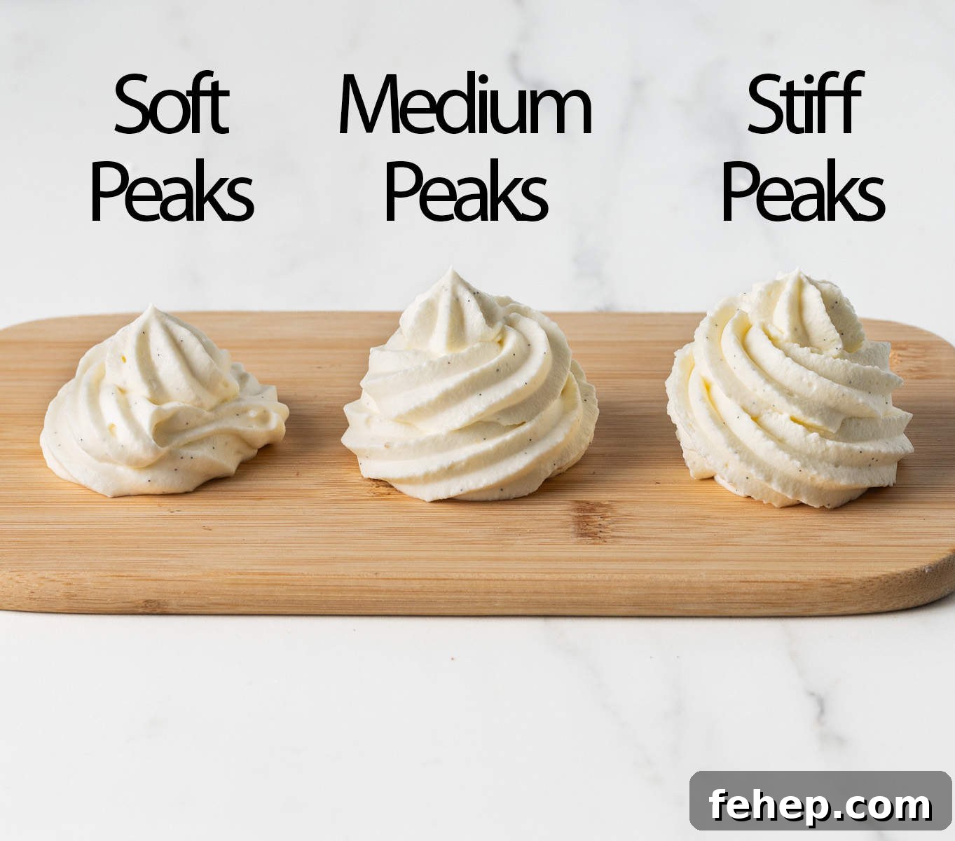 How to Make Classic Chantilly Cream (Crème Chantilly) 5 Dollops of chantilly cream at different whipping stages, piped over a small wooden board.