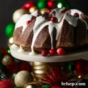 gingerbread bundt cake on a cake stand with christmas decorations behind it.