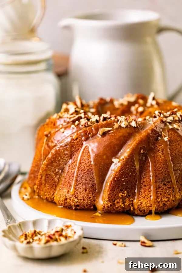 butter pecan pound cake on a serving plate topped with caramel and chopped pecans.