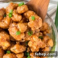 teriyaki cauliflower in a bowl topped with green onions and sesame seeds