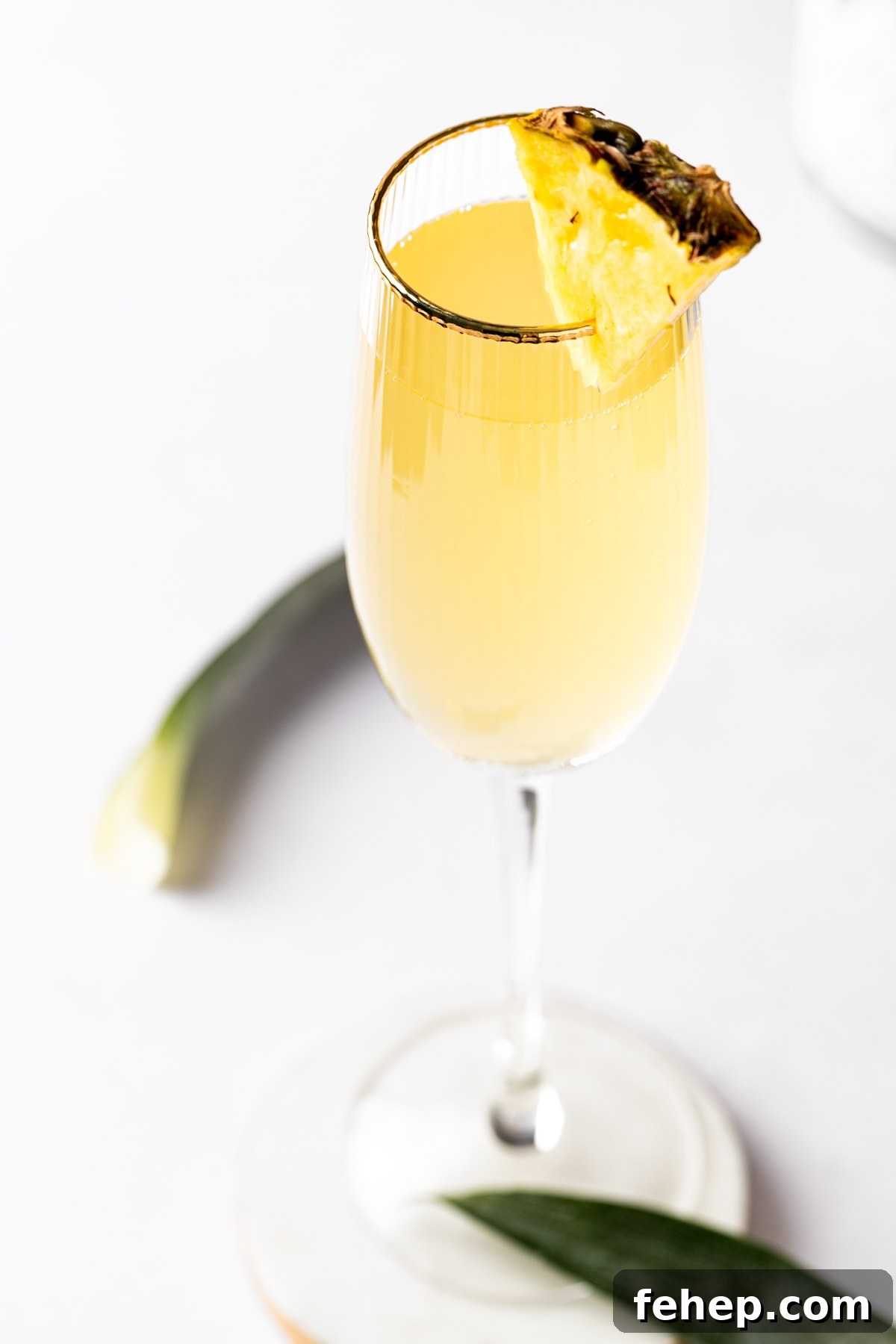 Pineapple Mimosa Cocktail: Tropical Brunch Sparkler 2 A pineapple mimosa in a champagne flute, garnished with a pineapple slice.