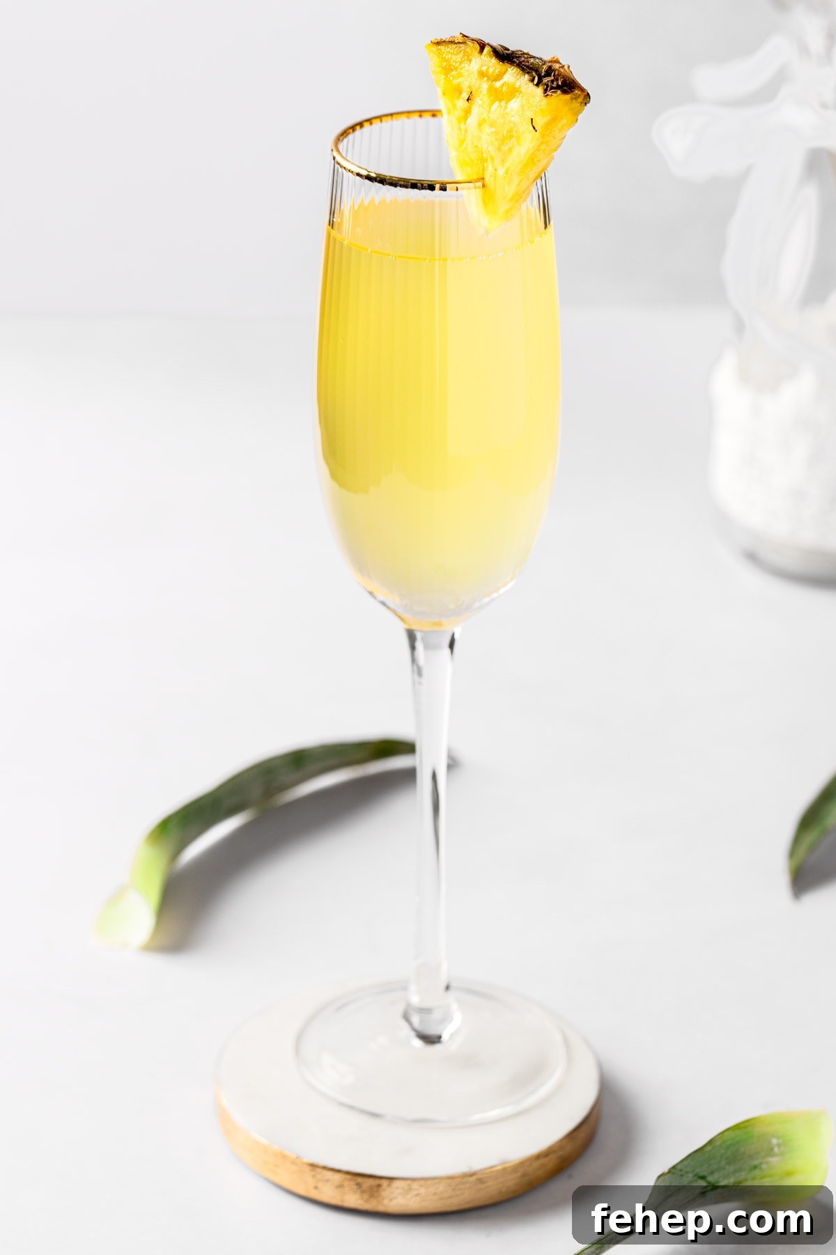Pineapple Mimosa Cocktail: Tropical Brunch Sparkler 6 A pineapple mimosa garnished with a pineapple slice, on a white background.