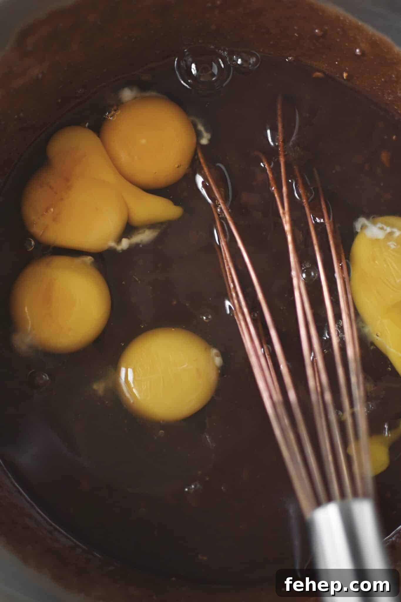 Placing the eggs into the cooled butter, chocolate and sugar mixture.