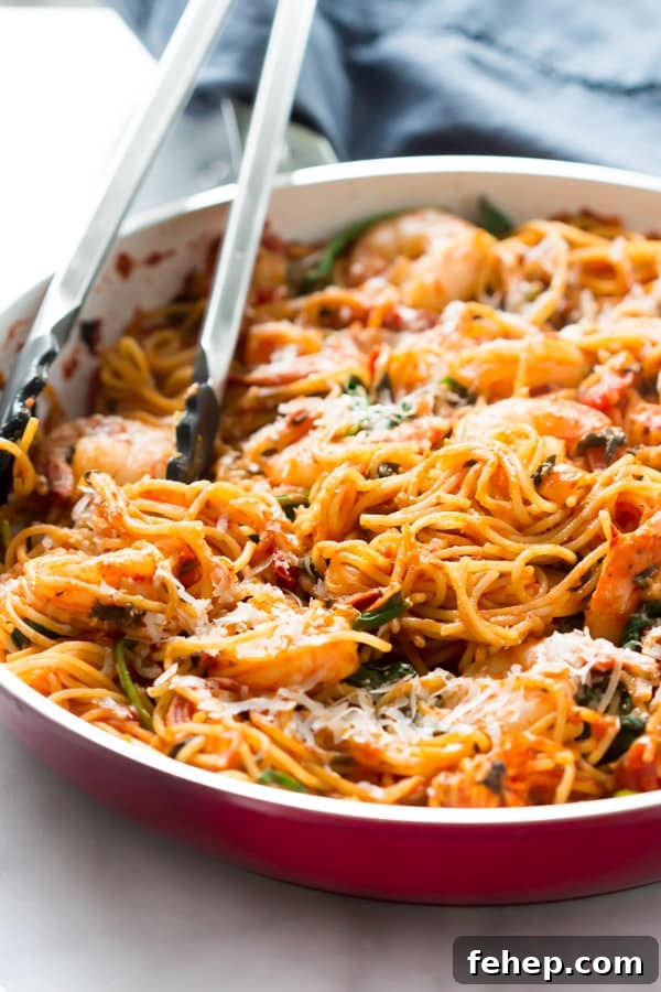 Sausage, Asparagus & Quinoa Pasta Recipe for Weeknights 5 Shrimp pasta in a skillet with tongs inside.
