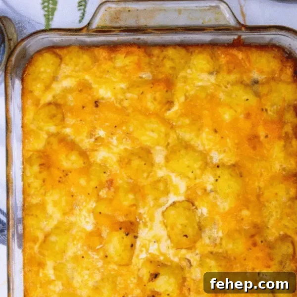 A glass baking dish filled with golden-brown tater tot breakfast casserole topped with melted cheese.