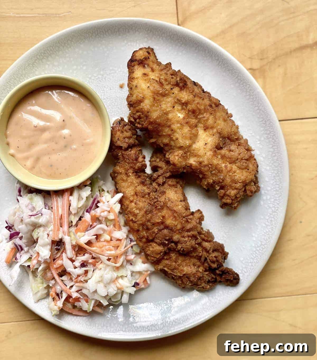 Copycat Raising Cane’s Sauce Recipe: Homemade Cane’s Dipping Sauce 10 Two homemade raising canes chicken tenders, canes sauce, and canes coleslaw on a white plate.