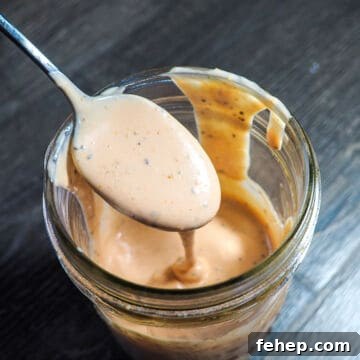 Copycat Raising Cane’s Sauce Recipe: Homemade Cane’s Dipping Sauce 11 A jar of homemade raising canes sauce dripping off of a spoon.