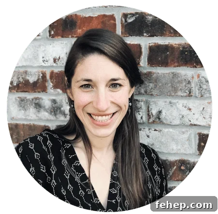 Copycat Raising Cane’s Sauce Recipe: Homemade Cane’s Dipping Sauce 3 A brunette with straight hair and green earrings wearing a gray shirt in front of a red and white brick wall.