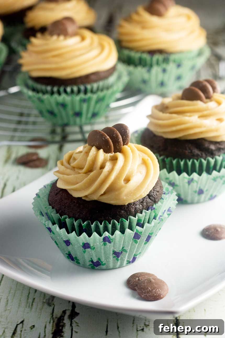 A closeup of a few chocolate stout cupcakes in green wrappers on a white plate.
