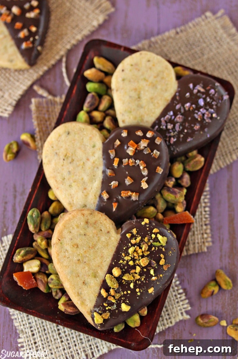Pistachio Shortbread Cookies Pistachio Shortbread Cookies - Three cookies displayed on a tray with pistachios. | From SugarHero.com