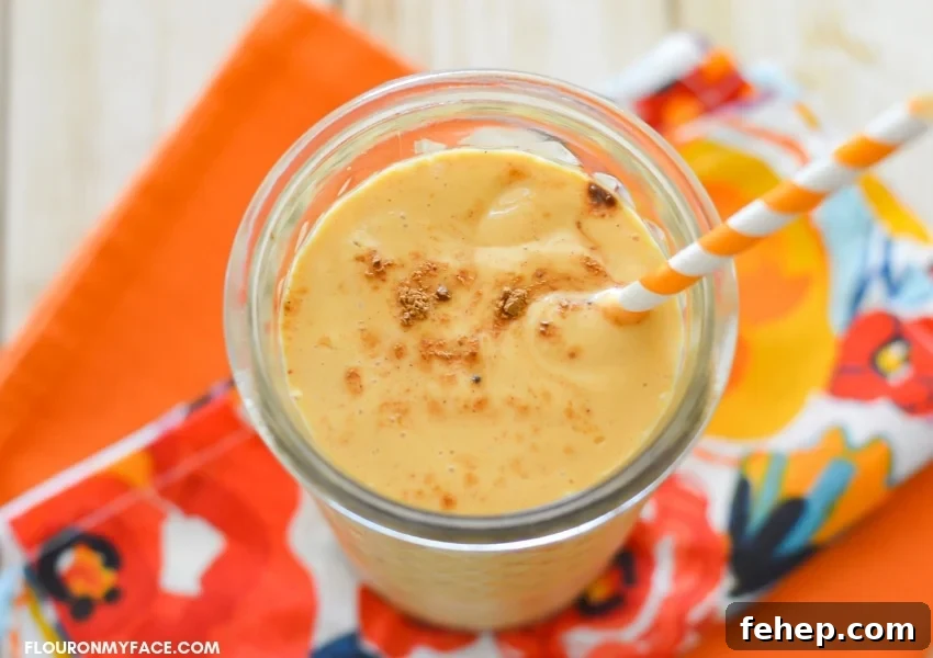 Creamy Pumpkin Smoothie — Autumn Spice Recipe for Fall Mornings 6 over head photo of a glass filled with a Pumpkin Spice Smoothie on top of a fall colored cloth napkin