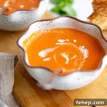 Bowl of Vitamix tomato soup on a wooden serving board.