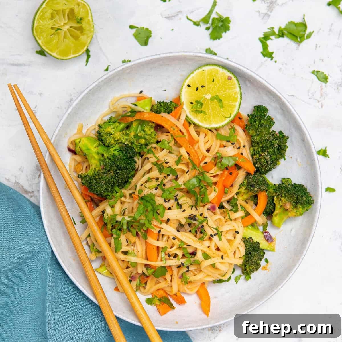 peanut butter noodles with vegetables in a bowl with chopsticks.