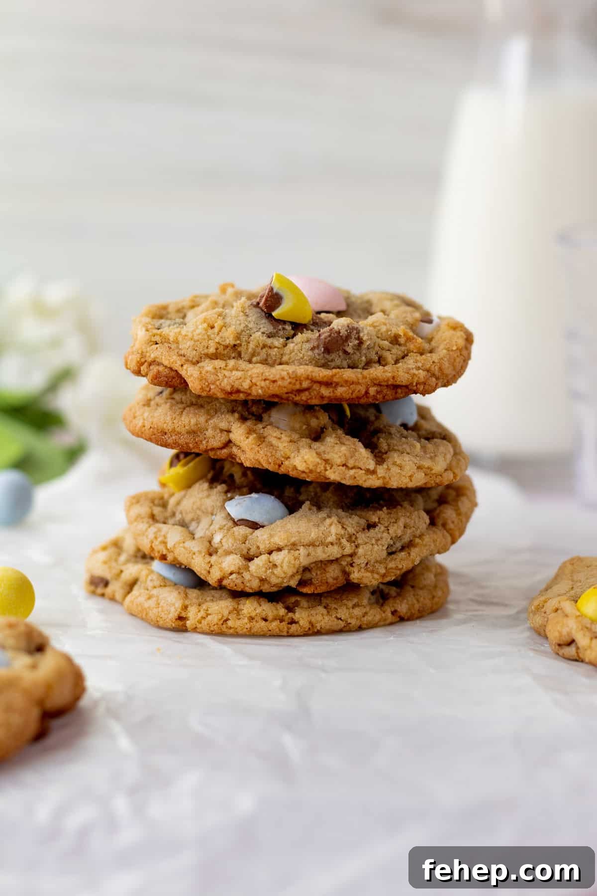 stack of mini egg cookies with glass pitcher of milk in background