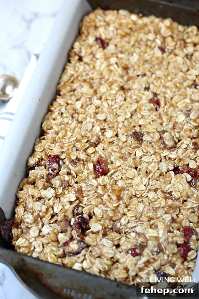 Cranberry Granola Bar Squares are a nutritious, moist, chewy granola bar square filled with oats, crispy rice, and dried cranberries. This is an easy, delicious, gluten-free and dairy-free snack recipe kids love!