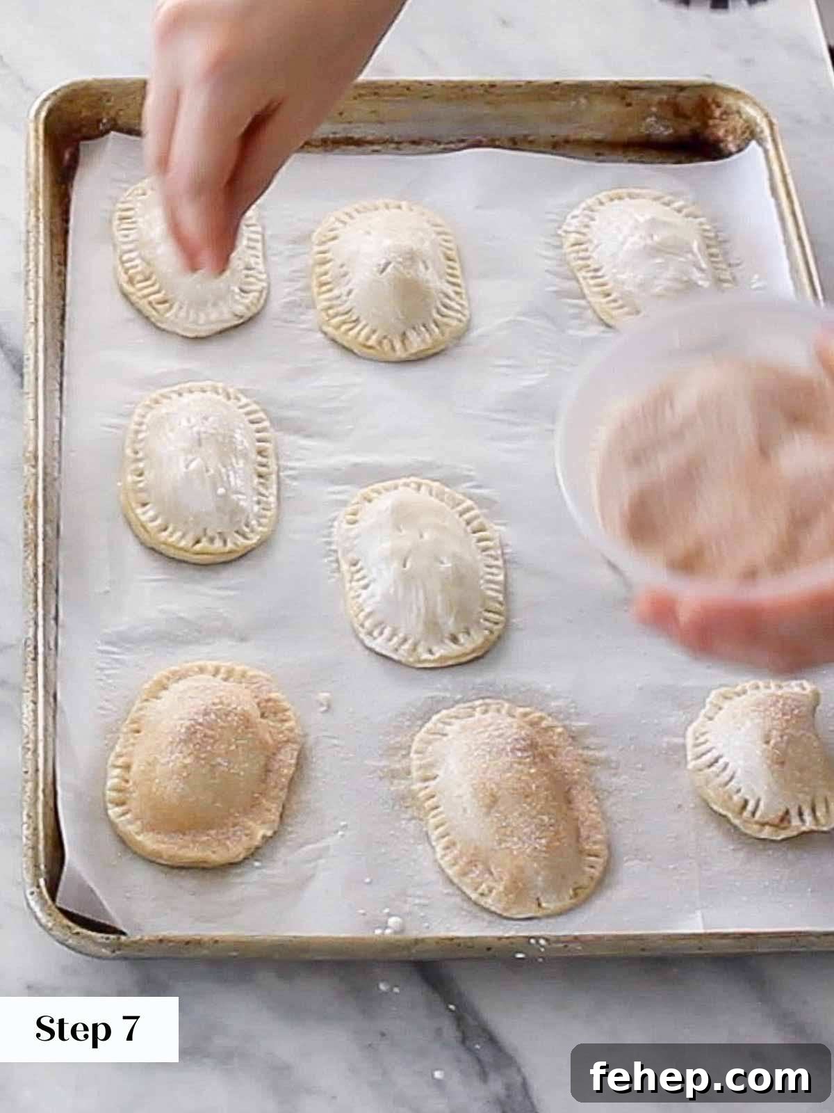 Mini Apple Hand Pies: Flaky Pocket Pies with Cinnamon Filling 11 brushing hand pies with cream and sprinkling cinnamon sugar on top.