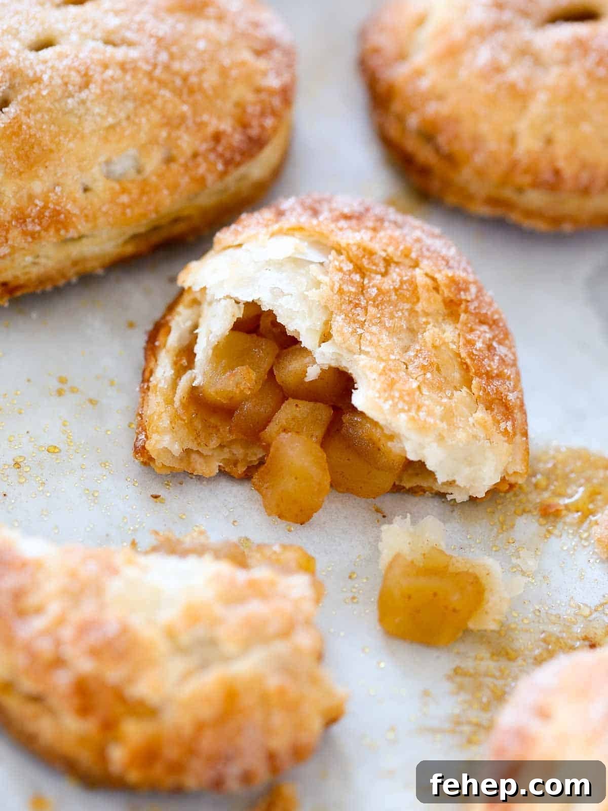 Mini Apple Hand Pies: Flaky Pocket Pies with Cinnamon Filling 13 hand pie opened on baking sheet with apple filling spilling out.