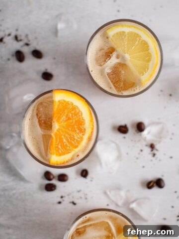three glasses of coffee lemonade decorated with lemons and orange slices, filled with ice, coffee beans and ice on the background,