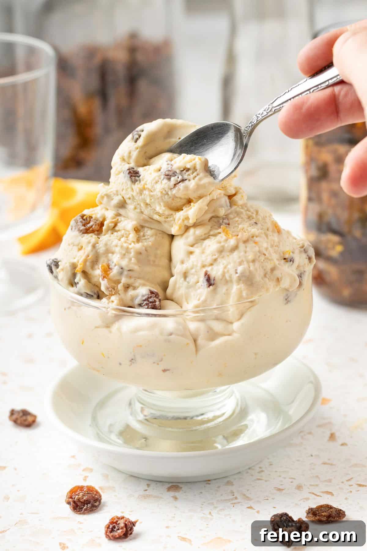 Fruit Mince Ice Cream in a glass bowl, sitting on a small white plate, with a silver spoon scooping up a mouthful.